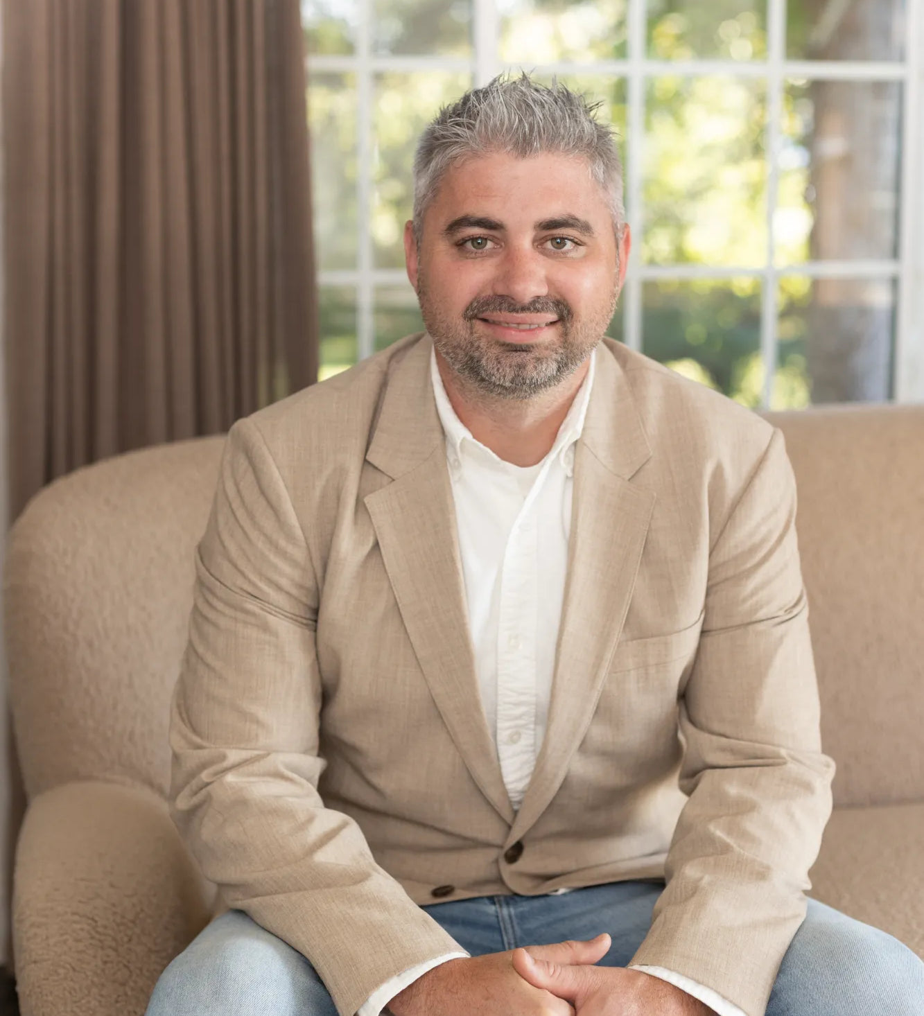 Co-owner Kyle Beachy sitting on a beige sofa at the S.Flynn home design and build office. 