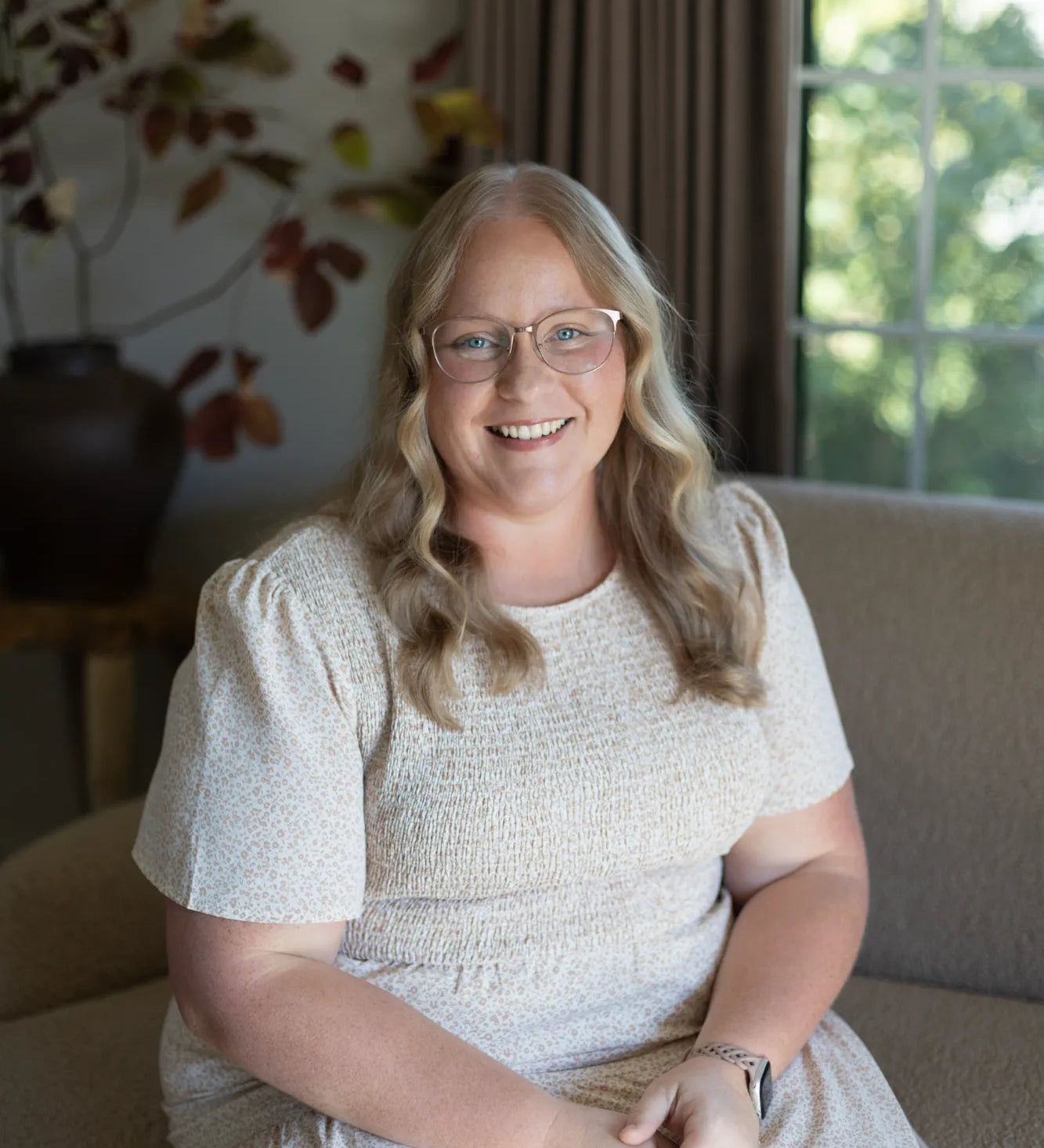 The accounts administrator sitting on a beige sofa in the S.Flynn Home Design + Build office with a bespoke vase behind her.
