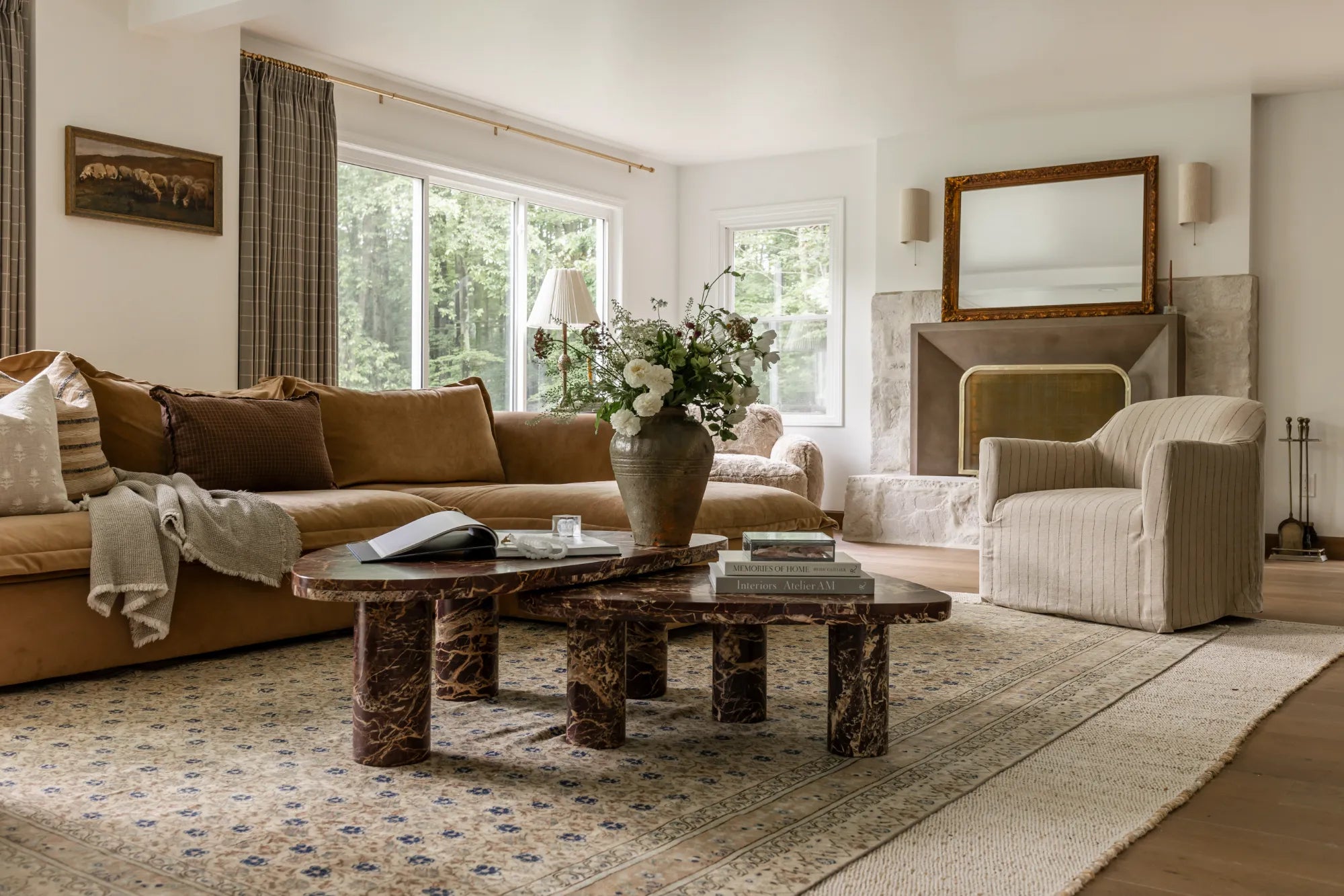Living room interior design and styling by S-Flynn-Home using products such as marble coffee tables, large textured sectionals, a striped armchair, and framed artwork.