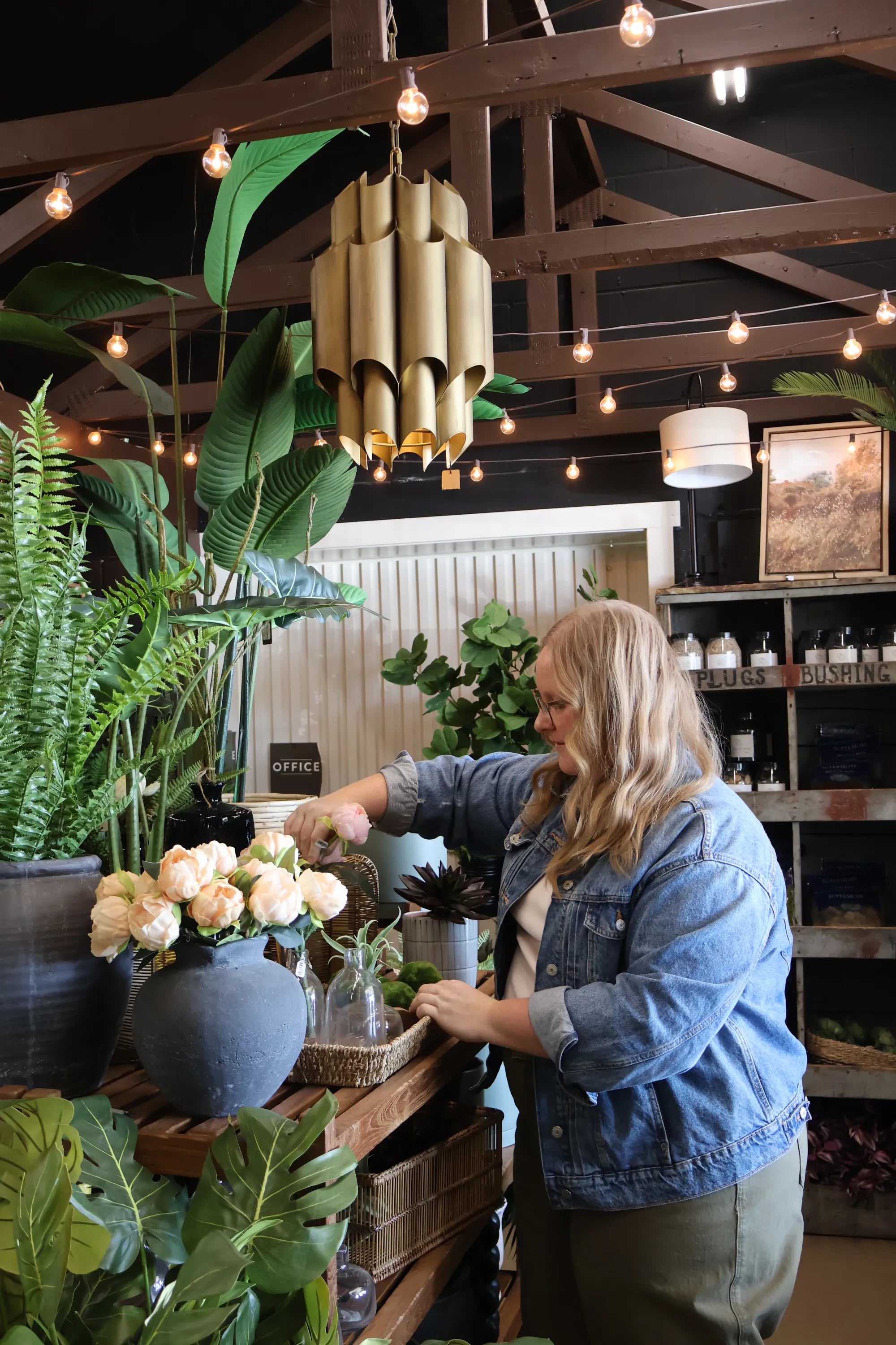 S.Flynn home customer shopping a styled table with artificial plants, bespoke vases, and wicker baskets. 