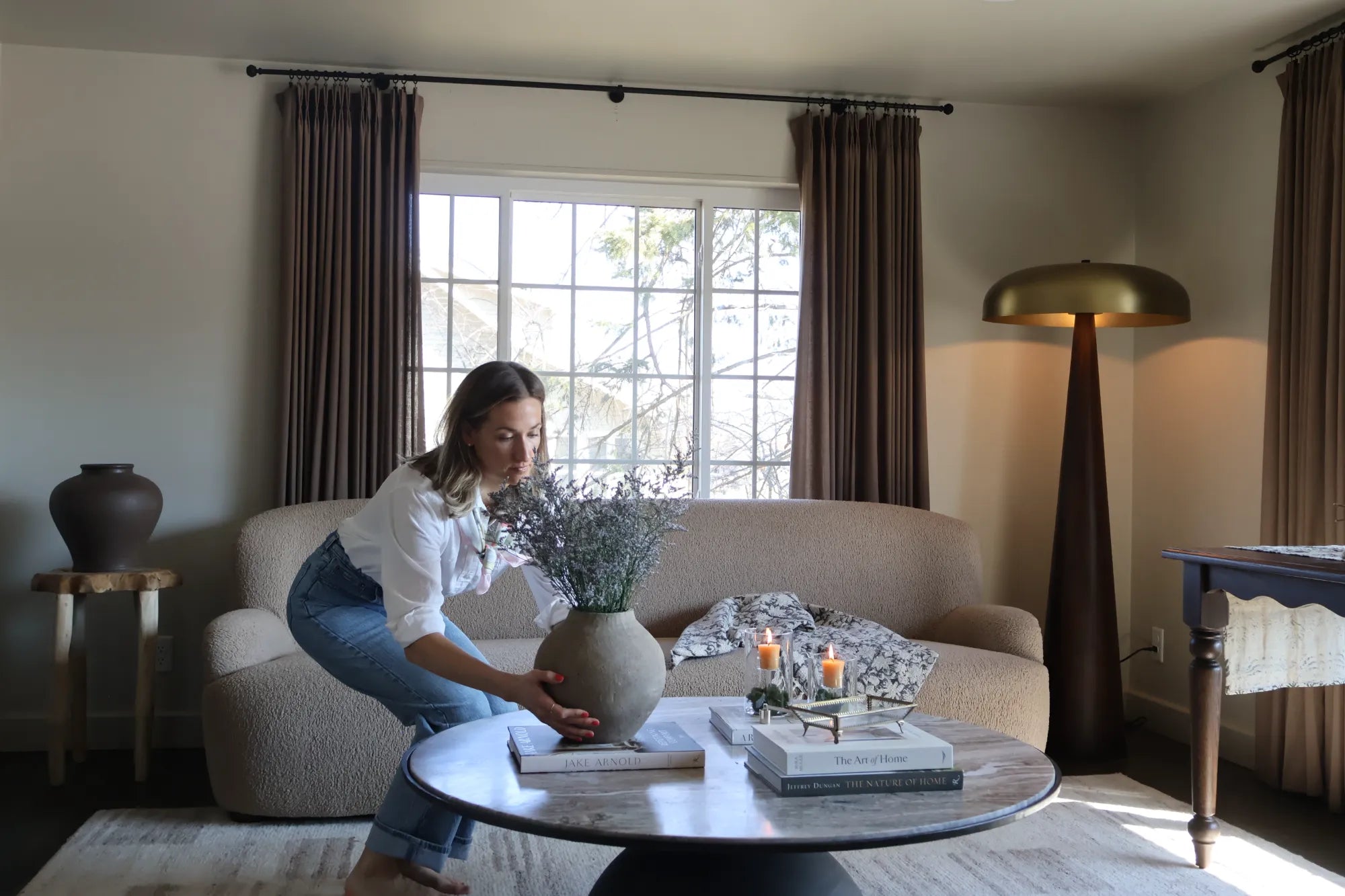 Founder of S.Flynn Home, Sadie Beachy, styling a marble coffee table by placing a bespoke vase of flowers and locally made beeswax candles on top of coffee table books. 