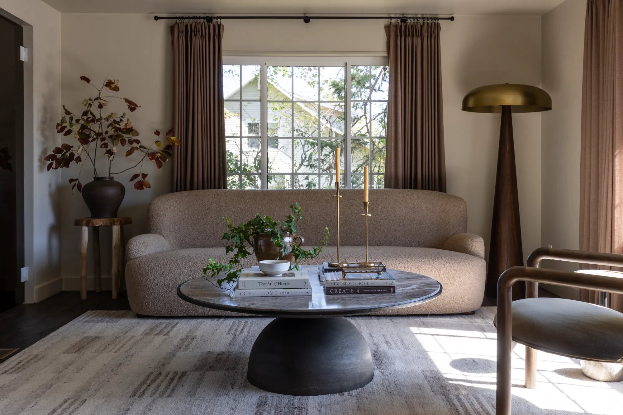 Living room space designed and styled by S. Flynn Home, showcasing a beige textured sofa behind a marble coffee table with decorative candles, books, and vases 